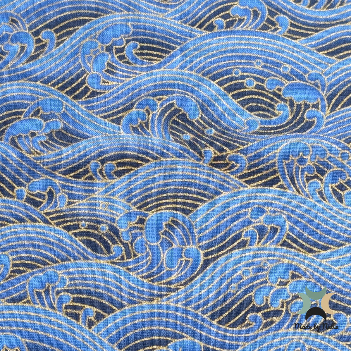A striking blue cotton fabric featuring flowing wave patterns with gold detailing.